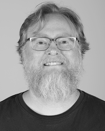 white man with short sandy blonde hair, a beard, and glasses