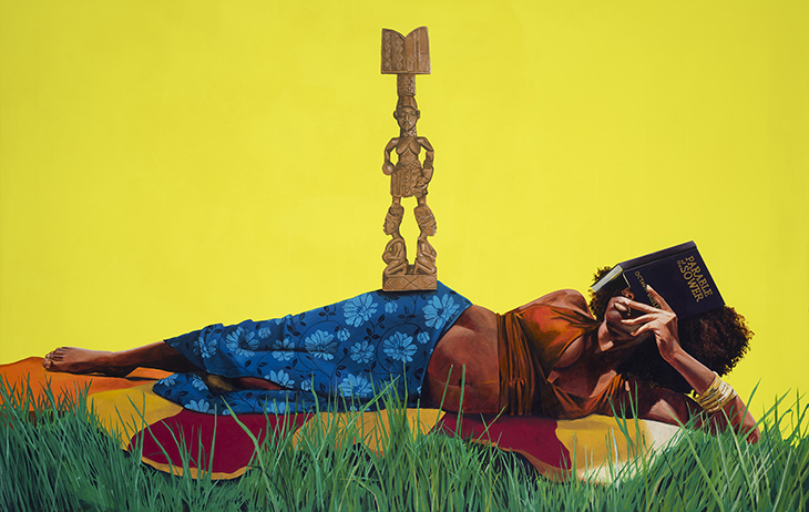 A pregnant Black woman reclines on a blanket in the grass; she covers her face with a book titled “Parable of the Sower” and a statue of a god-like figure balances on her hip