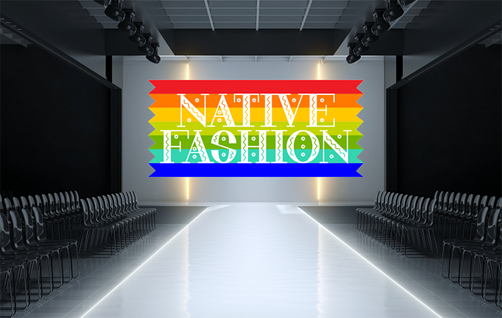 A runway illuminated with white light with chairs on both sides and the words "Native Fashion" against a rainbow design as a backdrop