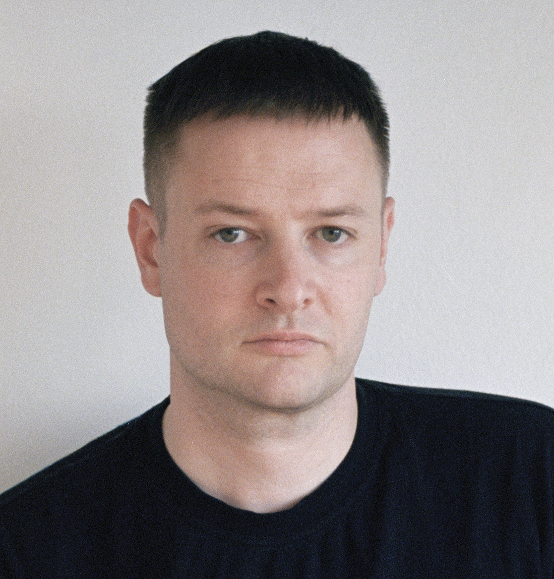 Headshot of a white man with short dark hear wearing a black shirt