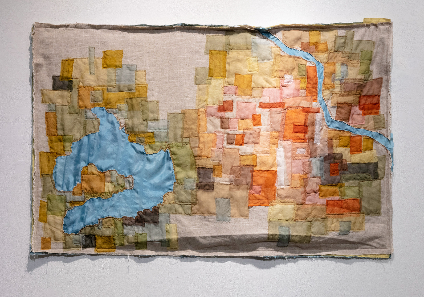 fabric map of Lawrence, KS, made from sewn squares and rectangles in a variety of shades of green, brown, yellow, and orange