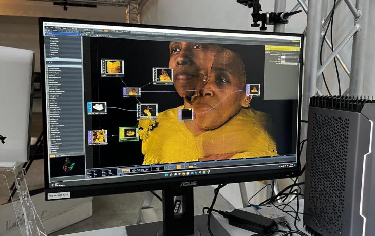 A computer screen displays a photo of a black woman wearing a yellow shirt