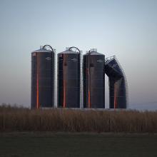 <a href="https://spencerartapps.ku.edu/collection-search#/object/58368" target="_blank"><i>Grain silos at sunset, north of Cullison, Kansas, November 2010</i> by Larry Schwarm</a>