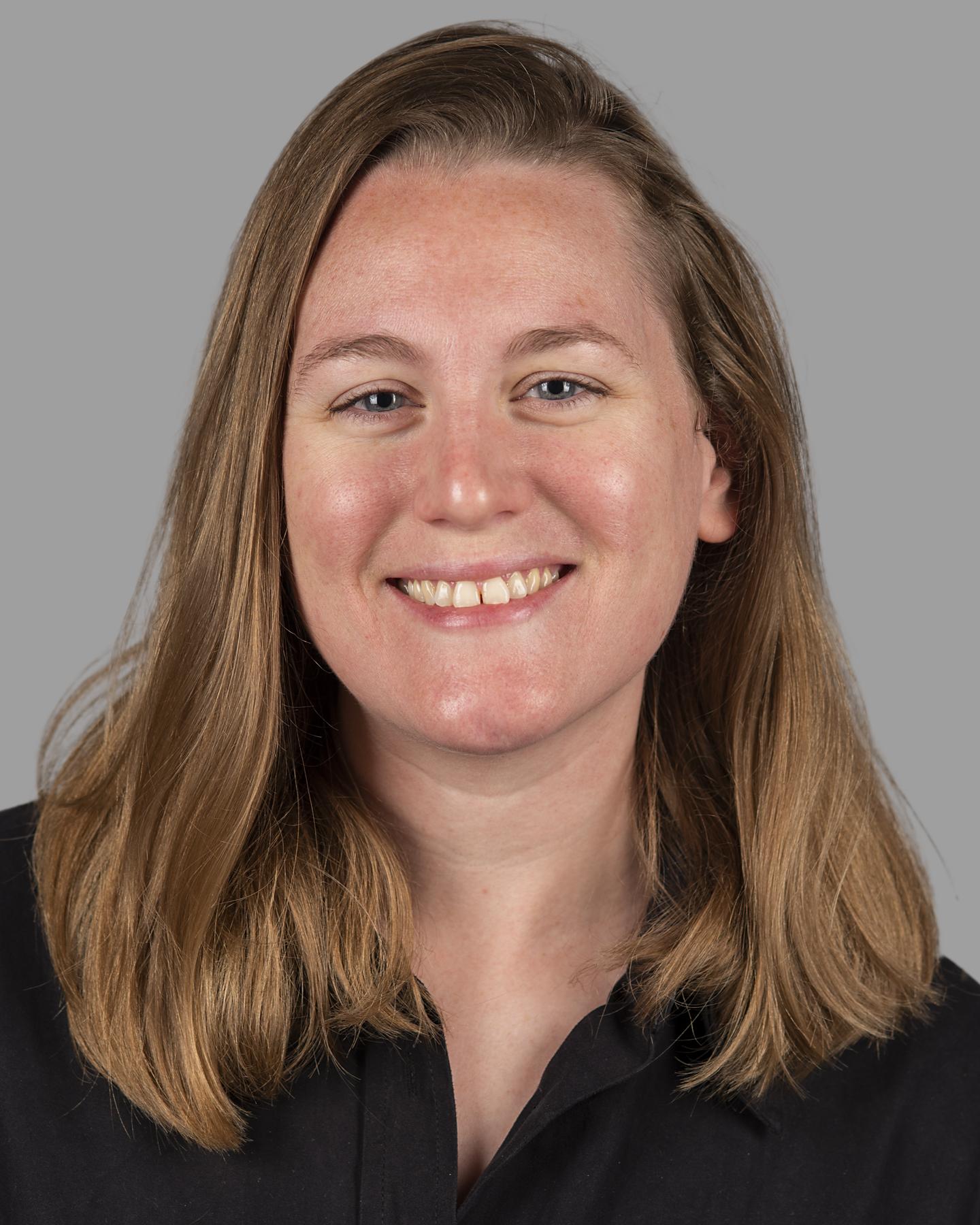 A white woman with shoulder-length blonde hair smiles at the camera