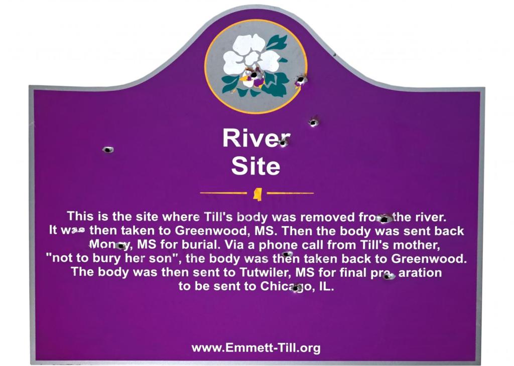 Purple sign with a white flower and the words "River Site" at top; it is riddled with several bullet holes