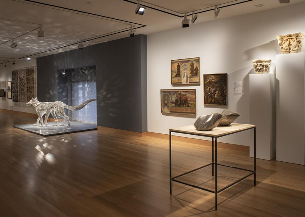 Image of a gallery space with a sparkly wolf sculpture on the floor and various works hung on the wall