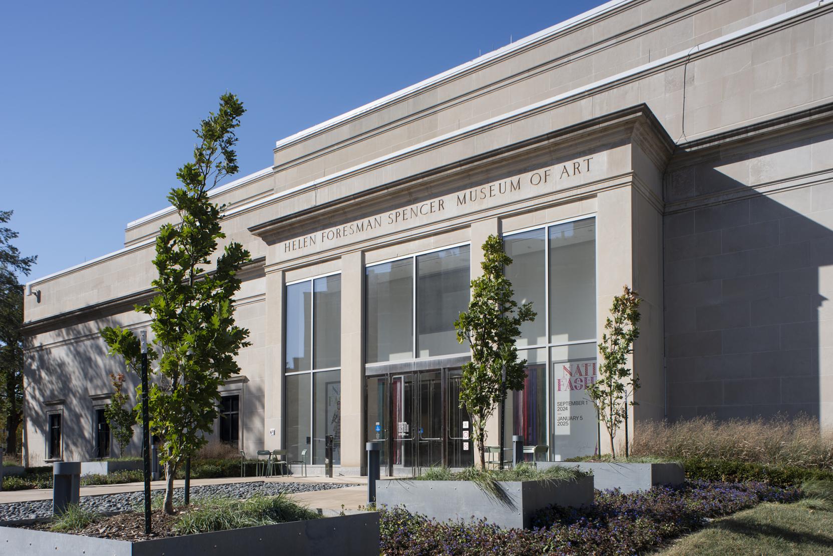 A view of the entrance to a classical stone building with large glass windows