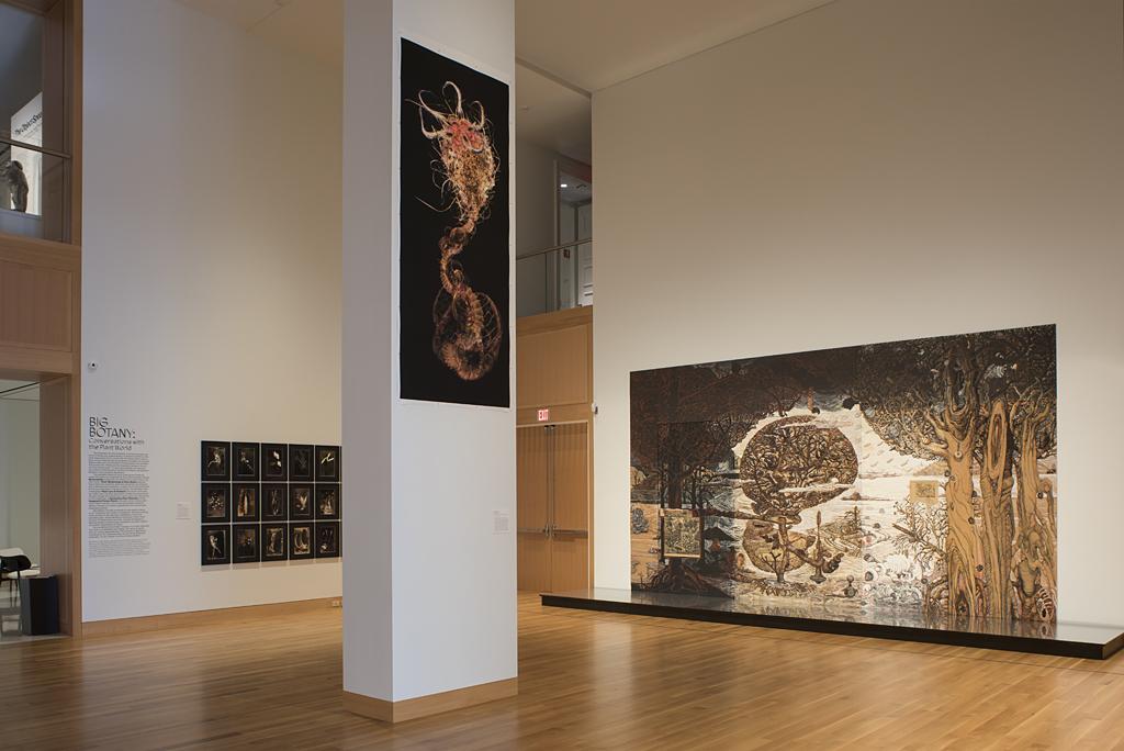 Gallery space with a column at center that includes an artwork depicting a red-brown creature on a black background