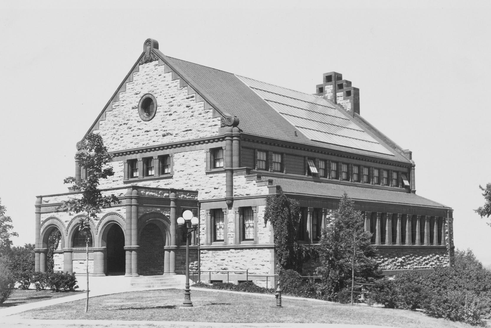 Black-and-white photo of a classic stone building with arches at the entrance