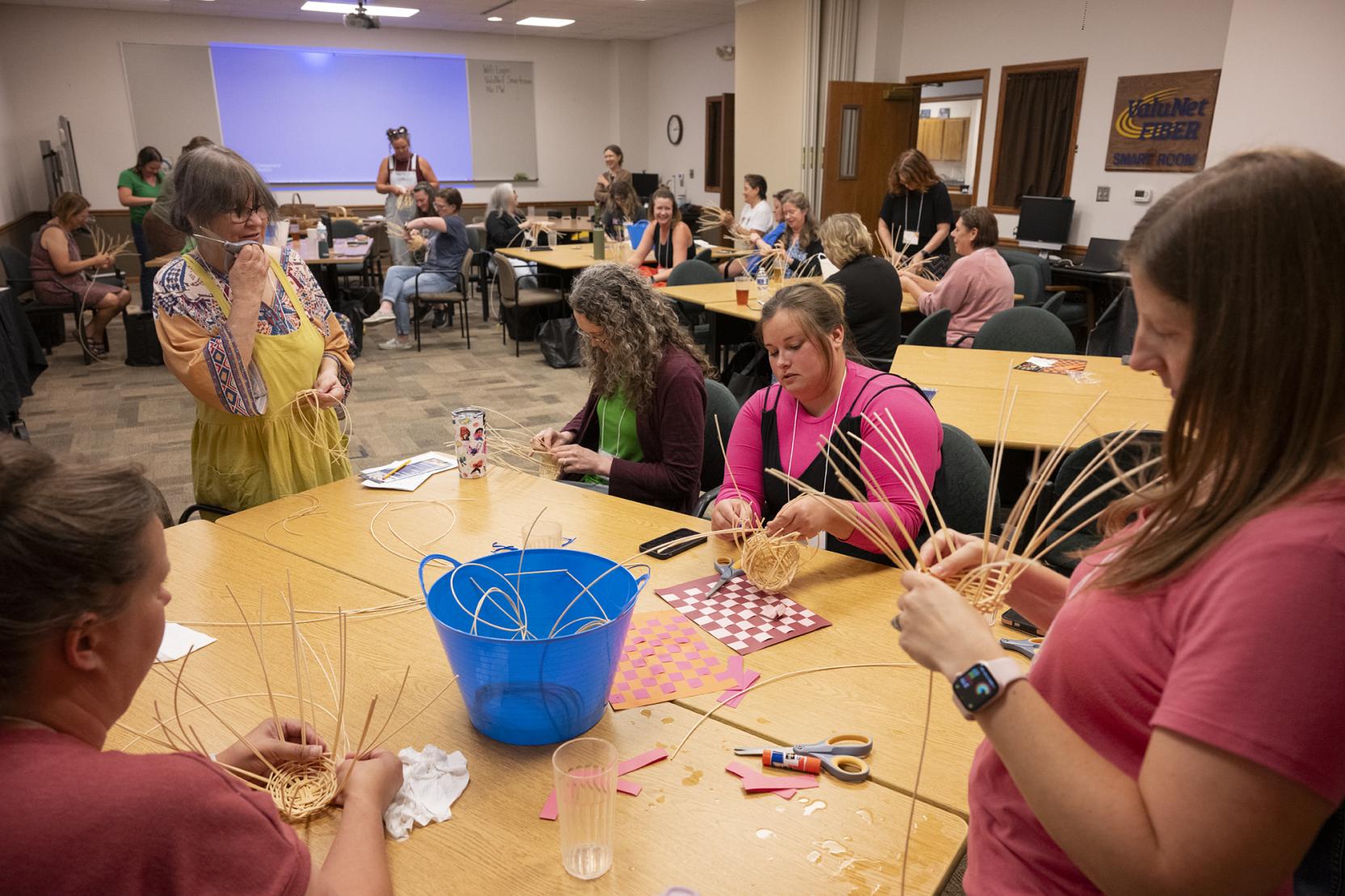 Photo of women weaving baskets while sitting around a table