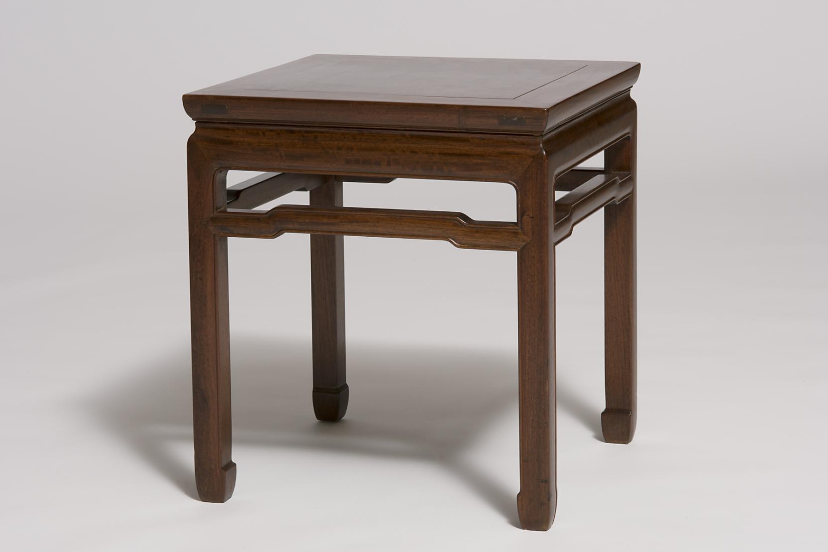 A brown, square wooden stool with four legs