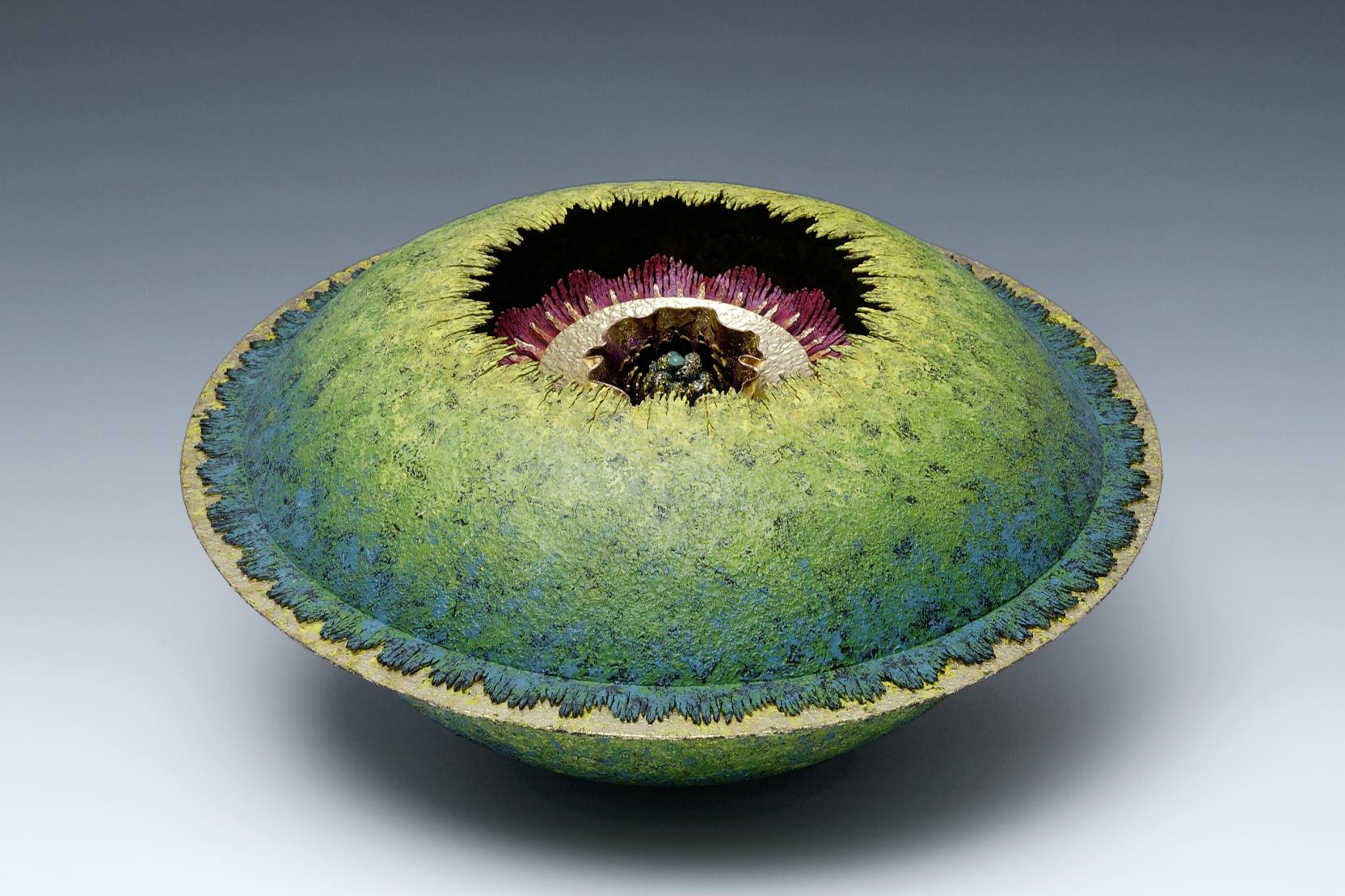 A blue globular container with a flat silver ring around the middle; an opening in the top center shows a multi-colored flower inside 