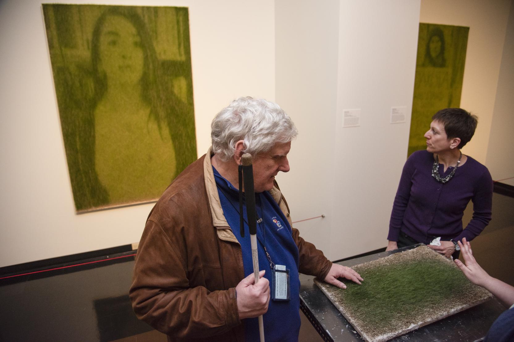 A man with white hair feels an artwork replica for visitors with low vision