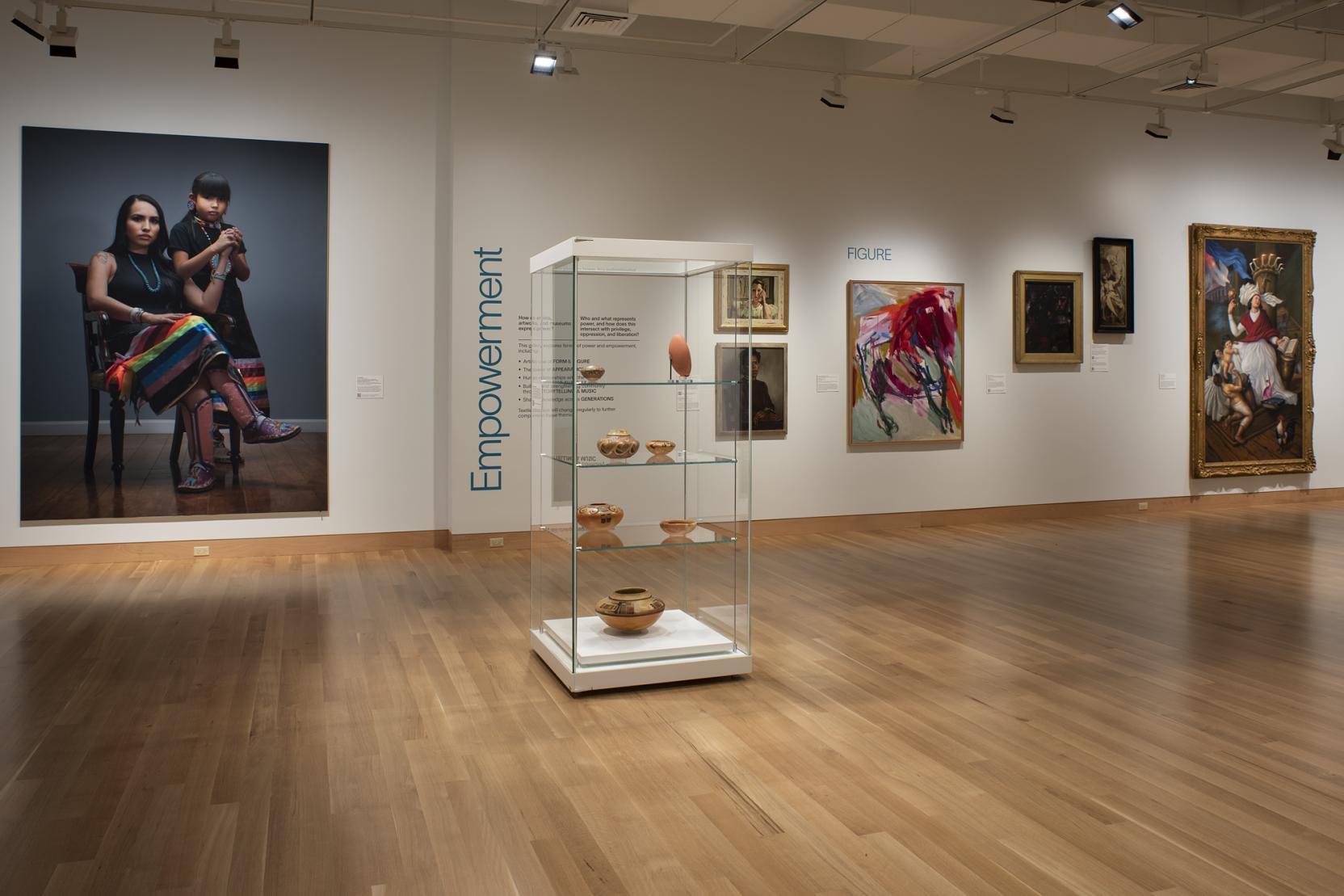 A museum gallery with wood floors and white walls with a large portrait photograph