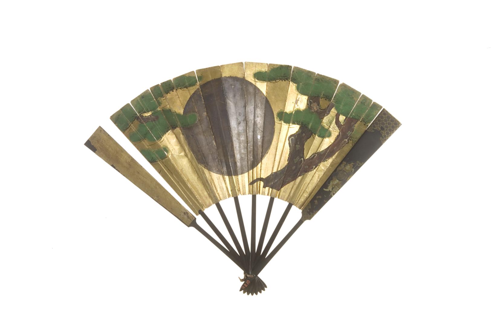 A gold folding fan painted with a large dark red circle centered between two trees