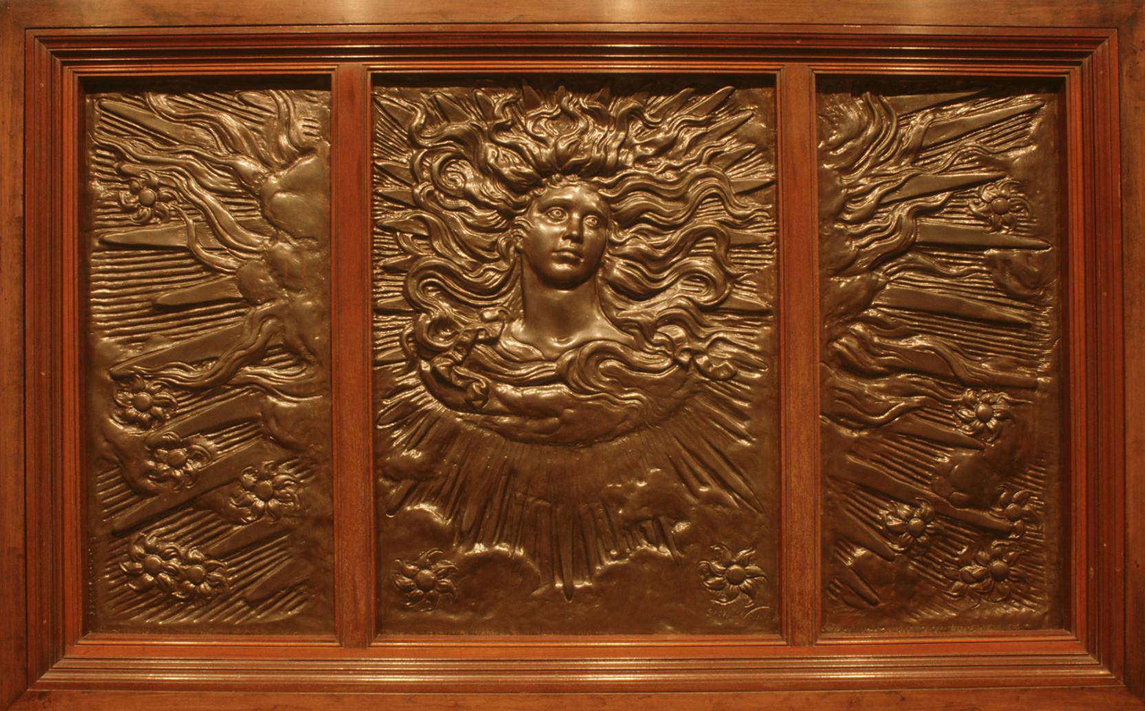 Three-paneled rectangular bronze relief framed in wood with a woman in the center whose long hair becomes the sun’s rays reaching flowers in the corners