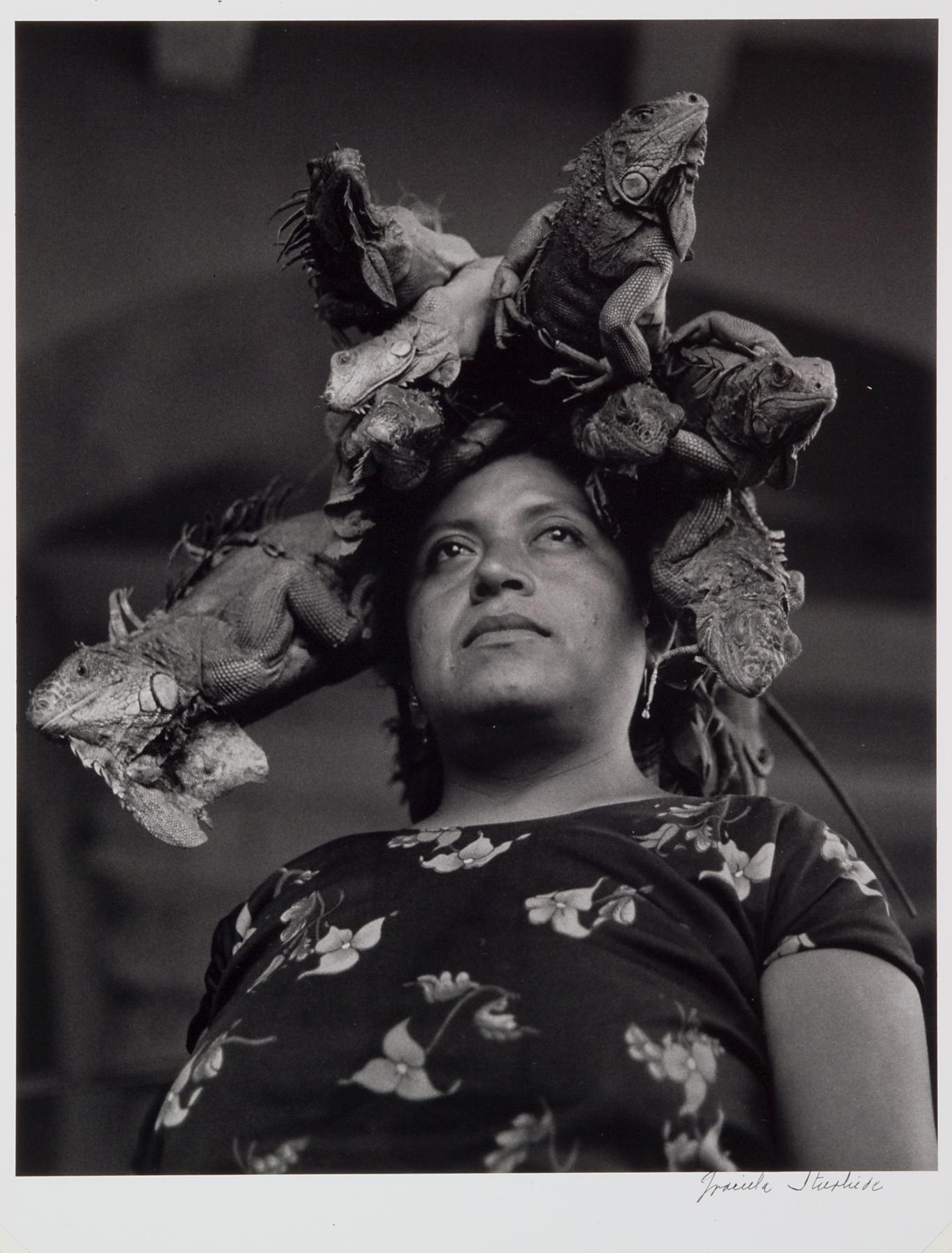 Black-and-white photo of a woman of color with several live iguanas sitting on her head