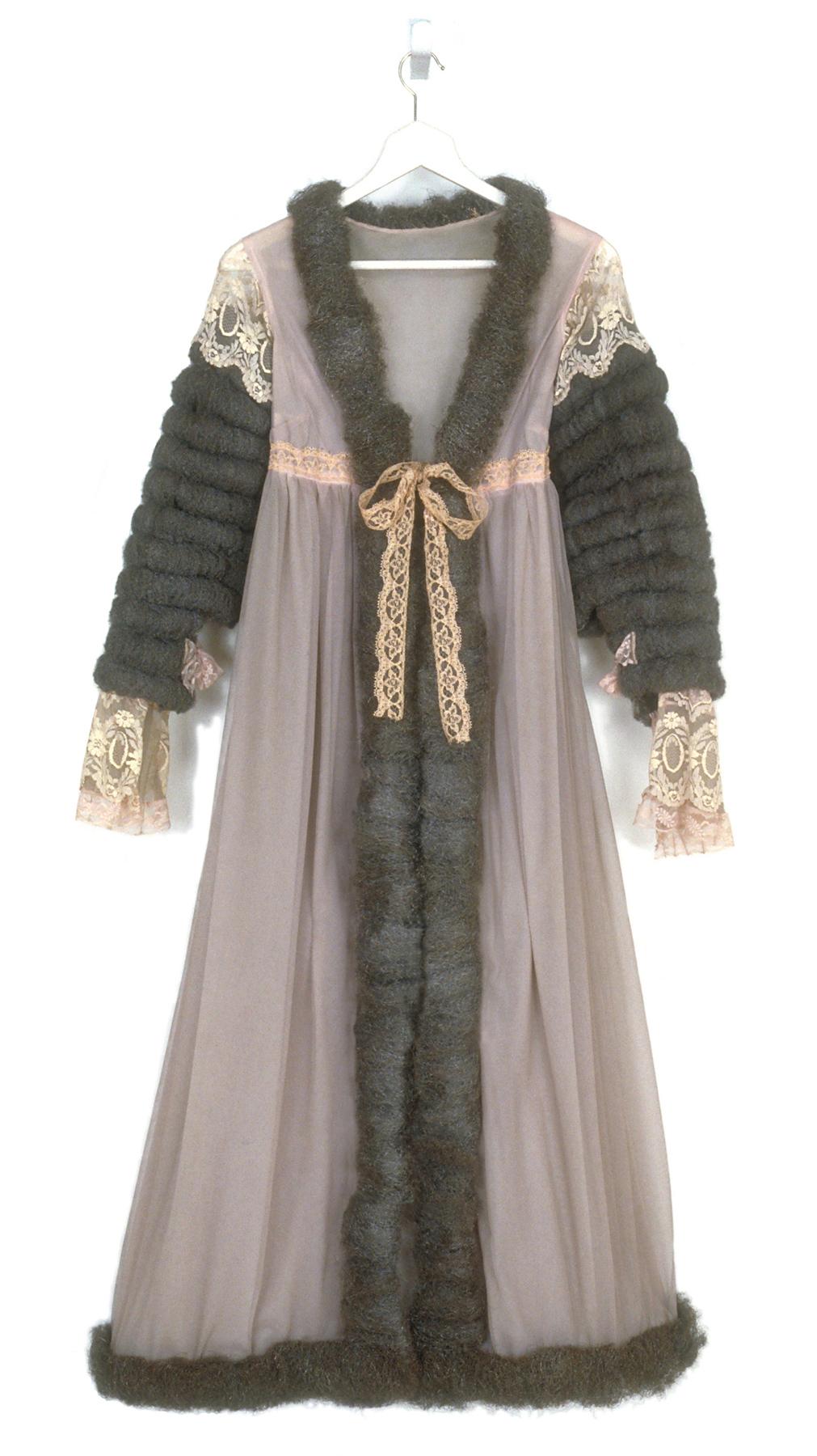 A robe made of pink sheer fabric with gray steel wool sleeves and trim and pink lace detailing hanging on a hanger