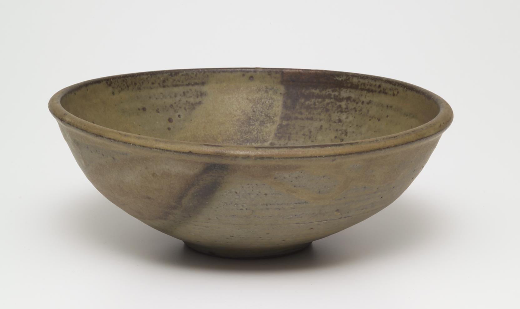 Shallow bowl with an earth-toned glaze, accented with splashes of yellow and black
