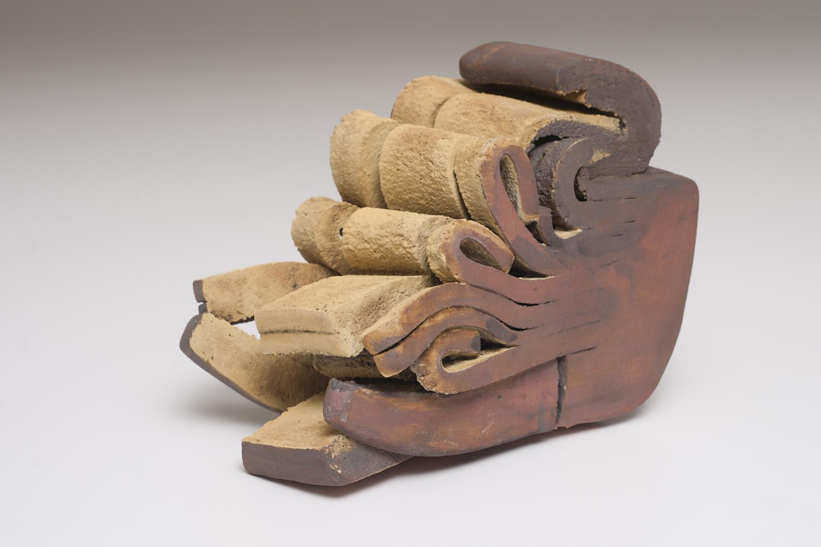 Sliced forms of clay stacked and curling upward on one side, forming an undulating edge