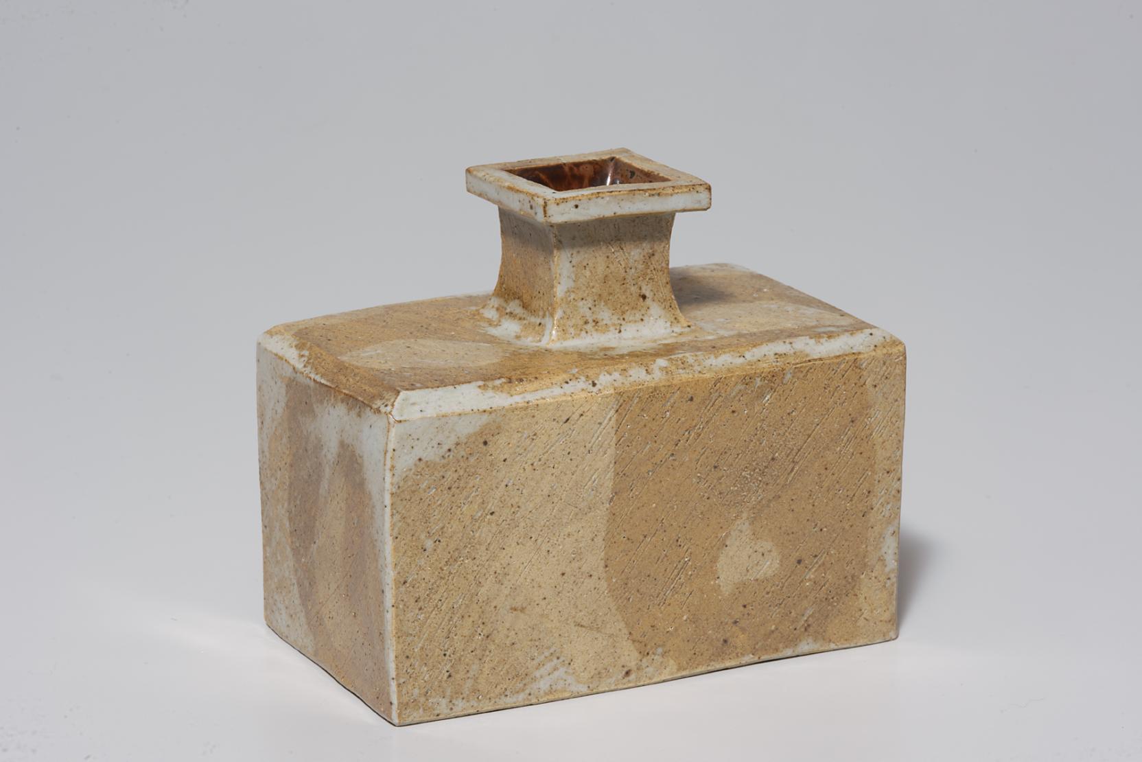 Bottle with a rectangular base and narrow four-sided neck, featuring a marbled pattern in yellow and white