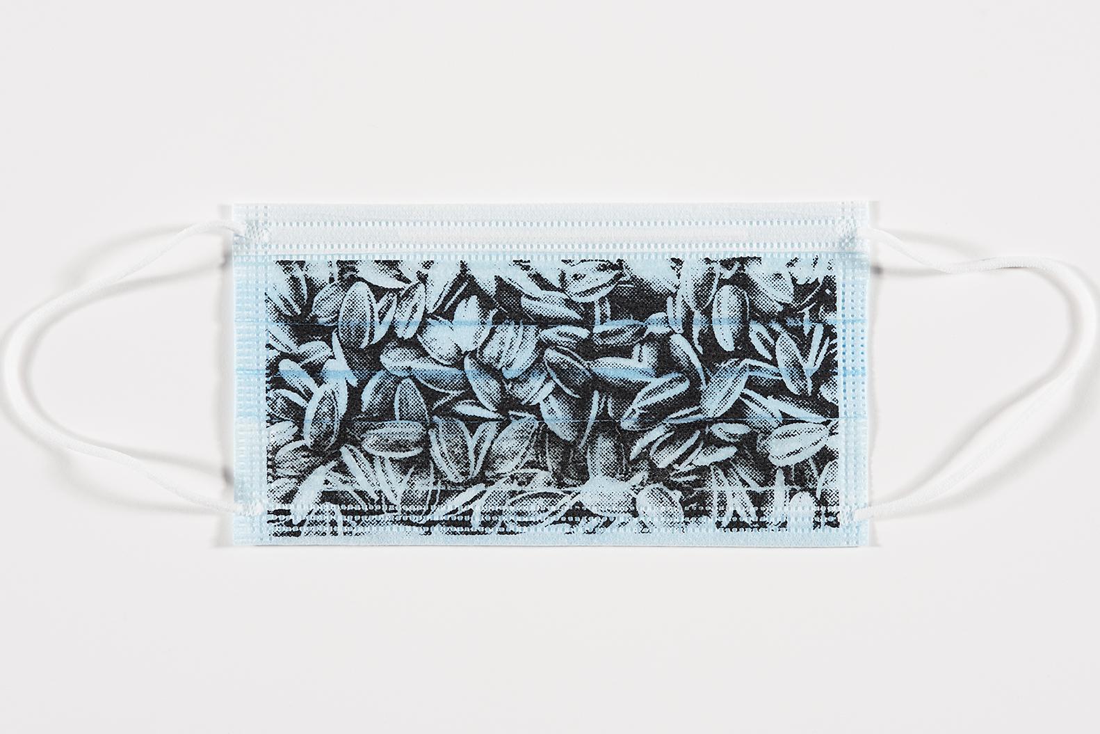 A light blue medical mask printed in black with an image of tightly packed sunflower seeds