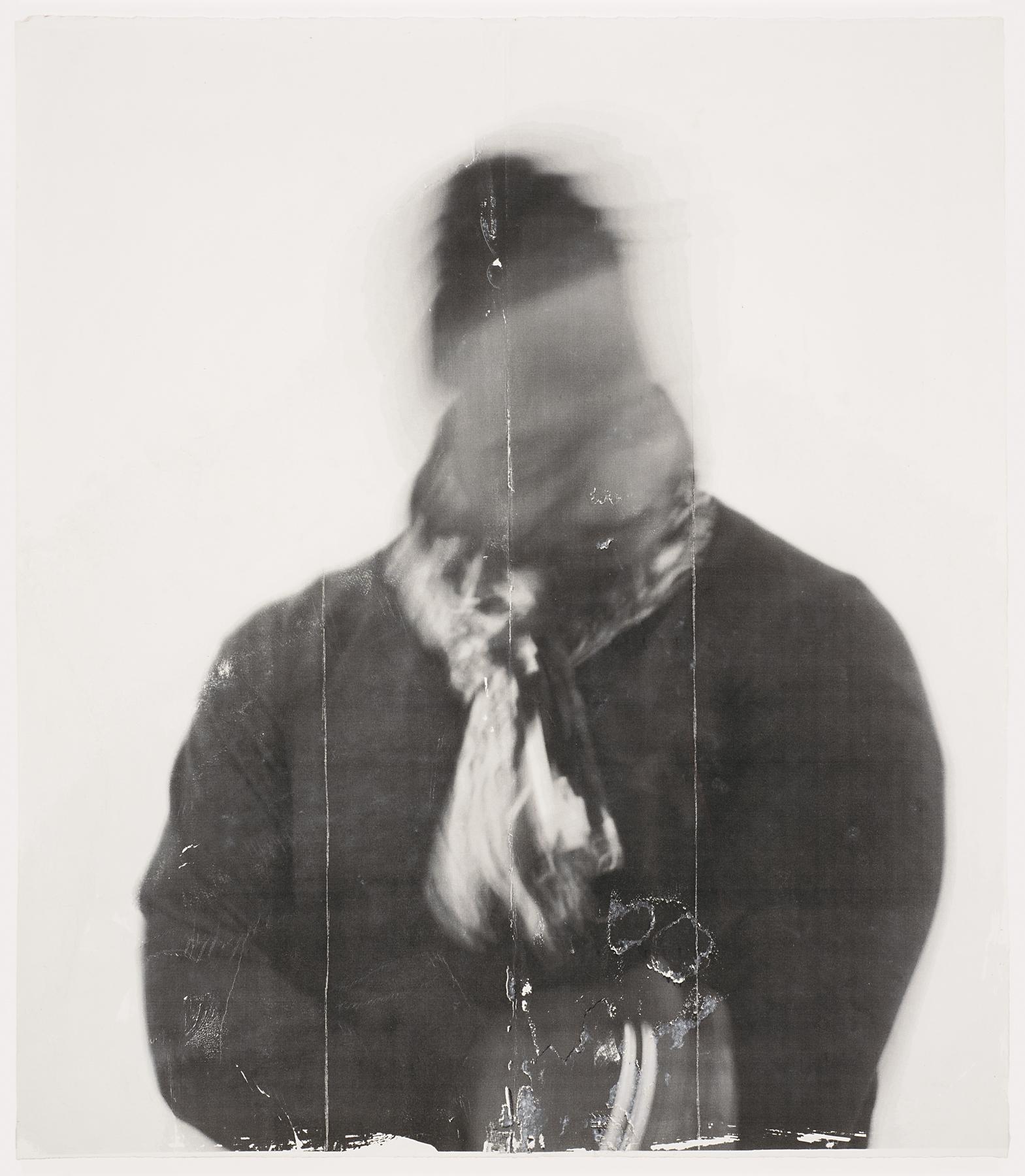 Black-and-white photograph of an adult from the waist up wearing a coat, scarf, and hat; their face is blurred 