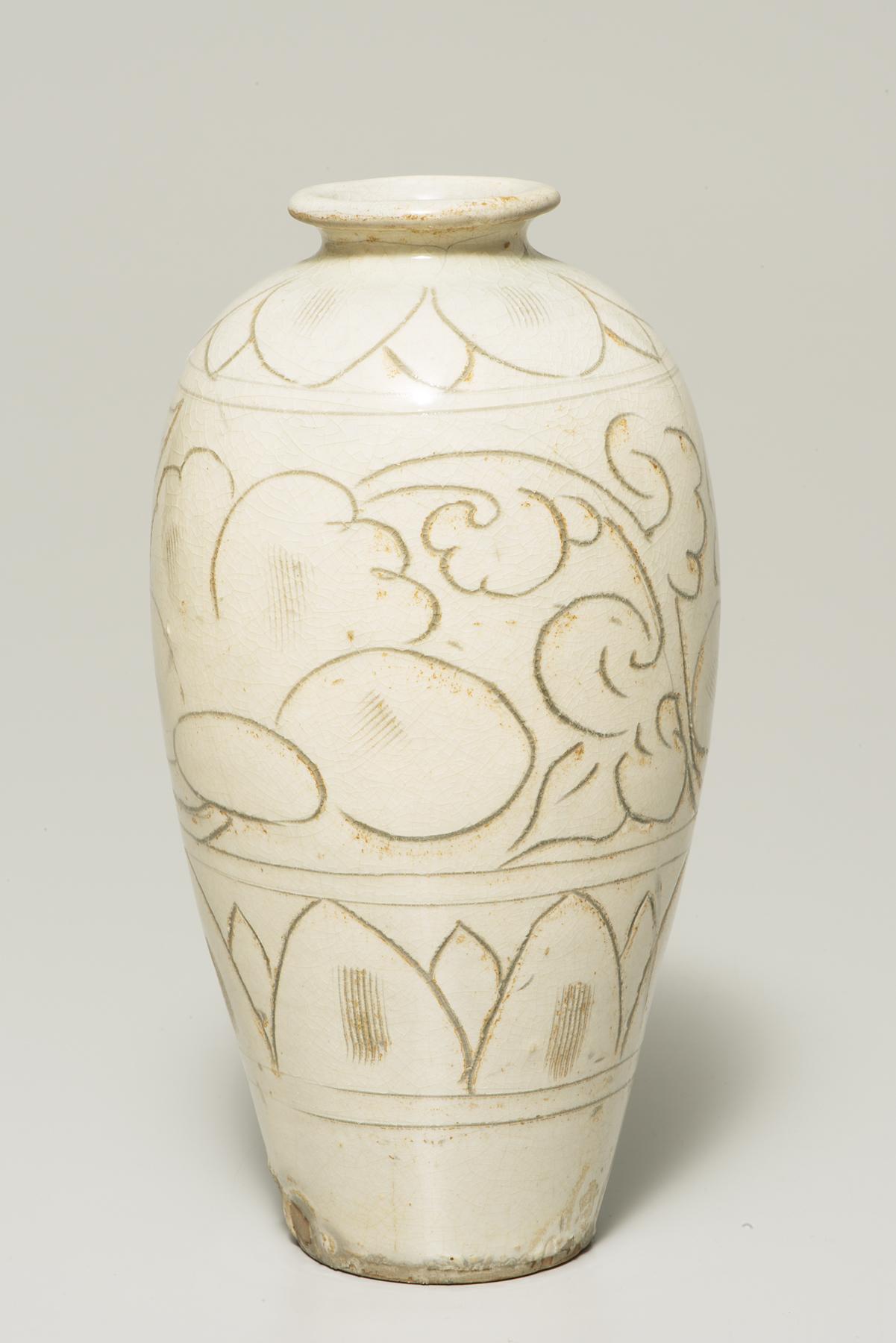 A tall, cream-colored jar that narrows at the bottom is decorated with various brown flower designs 