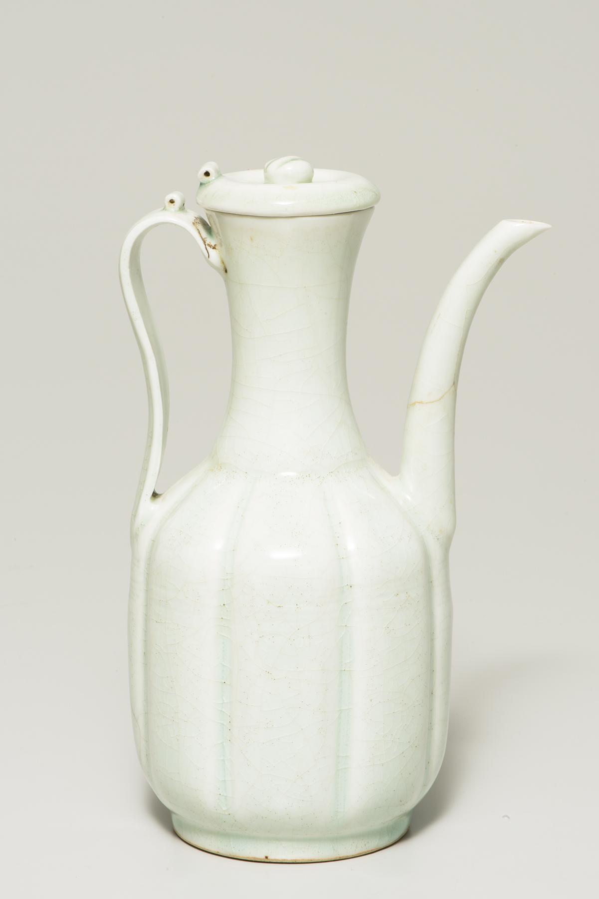 A tall white pitcher with a melon-shaped body and long spout
