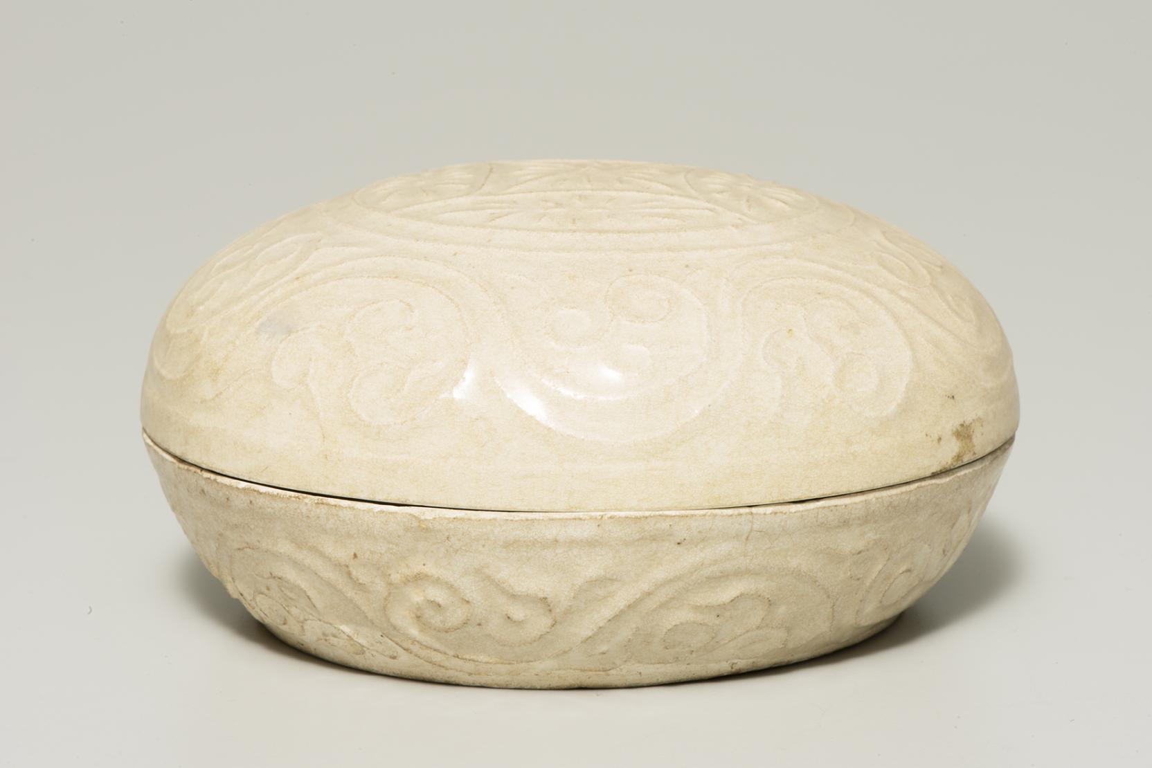 oval, cream-colored, lidded box with molded decoration