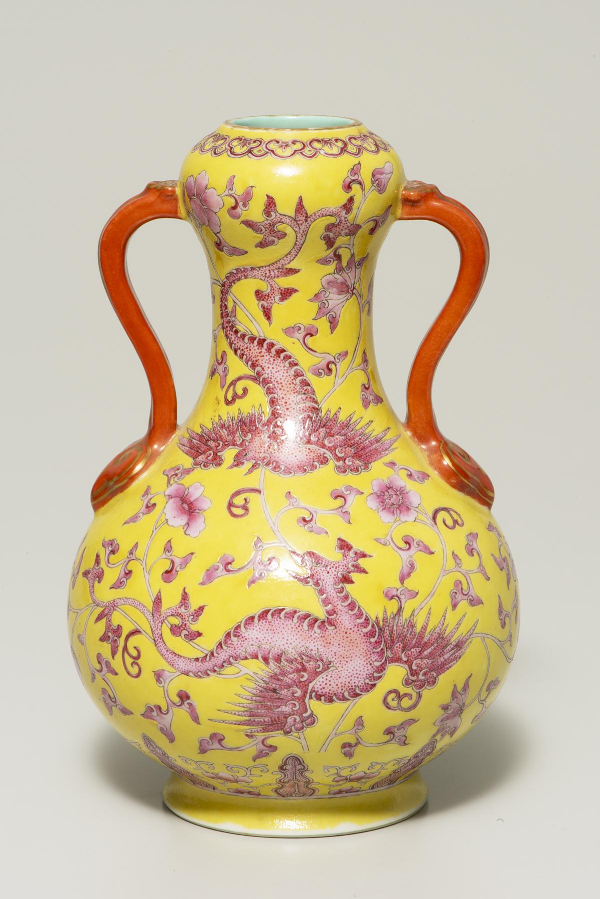 wide-bottomed yellow vase with two orange handles decorated with two pink birds flying among pink flowers