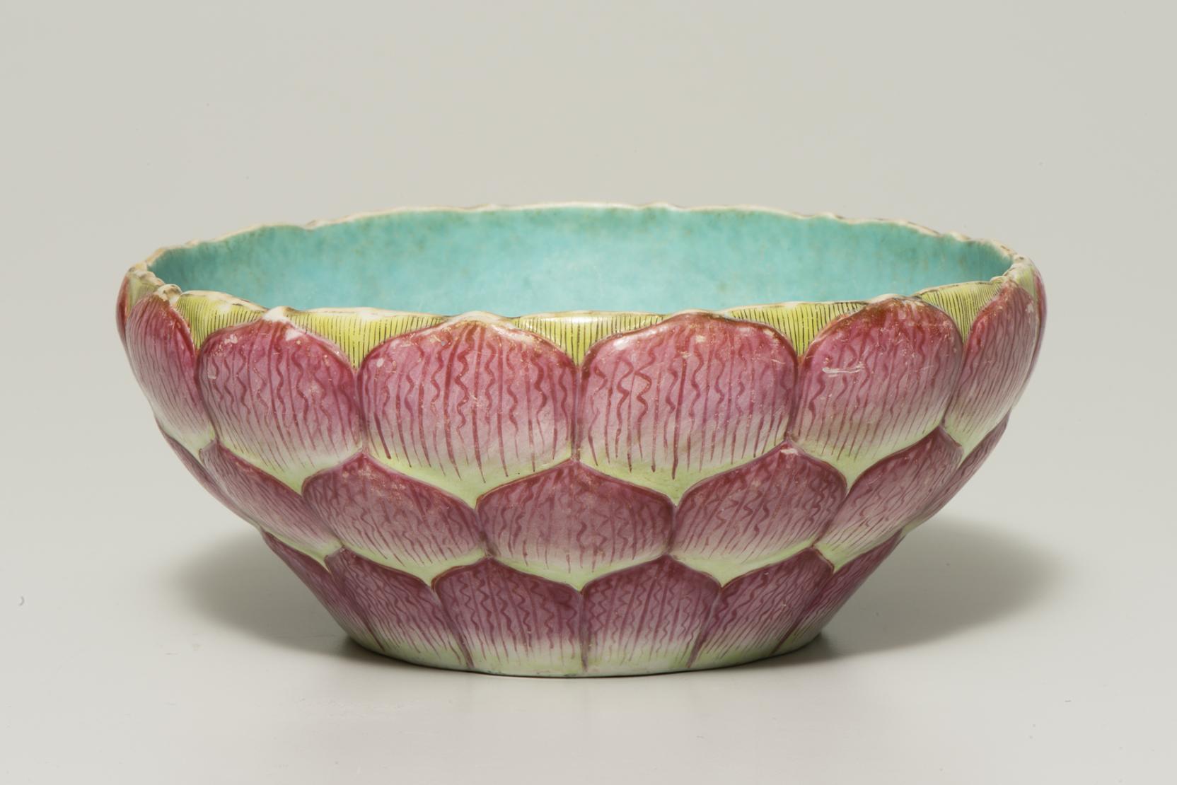 A yellow bowl covered with red petals is painted blue on the inside