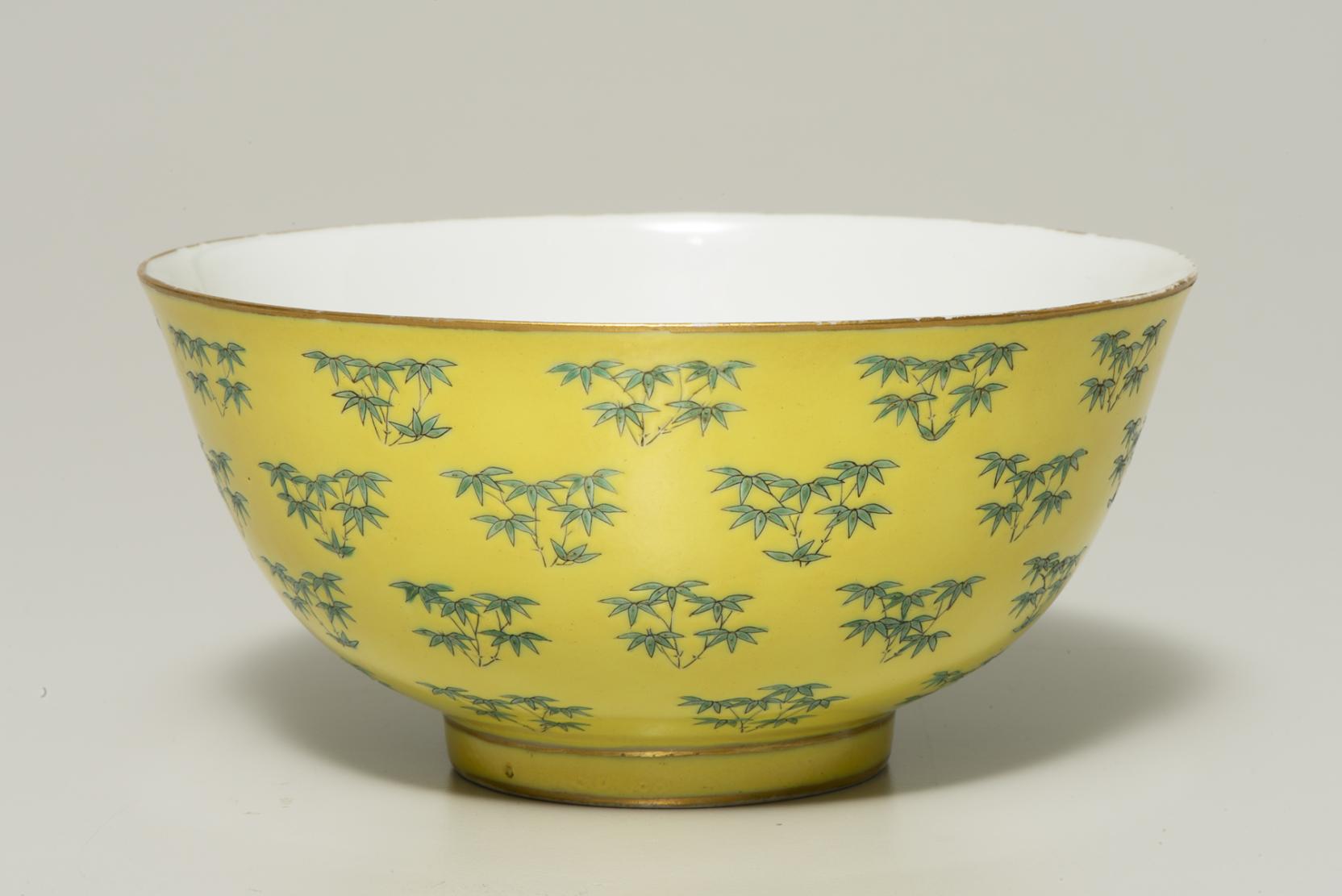 yellow bowl decorated with small clumps of bamboo that has a white interior