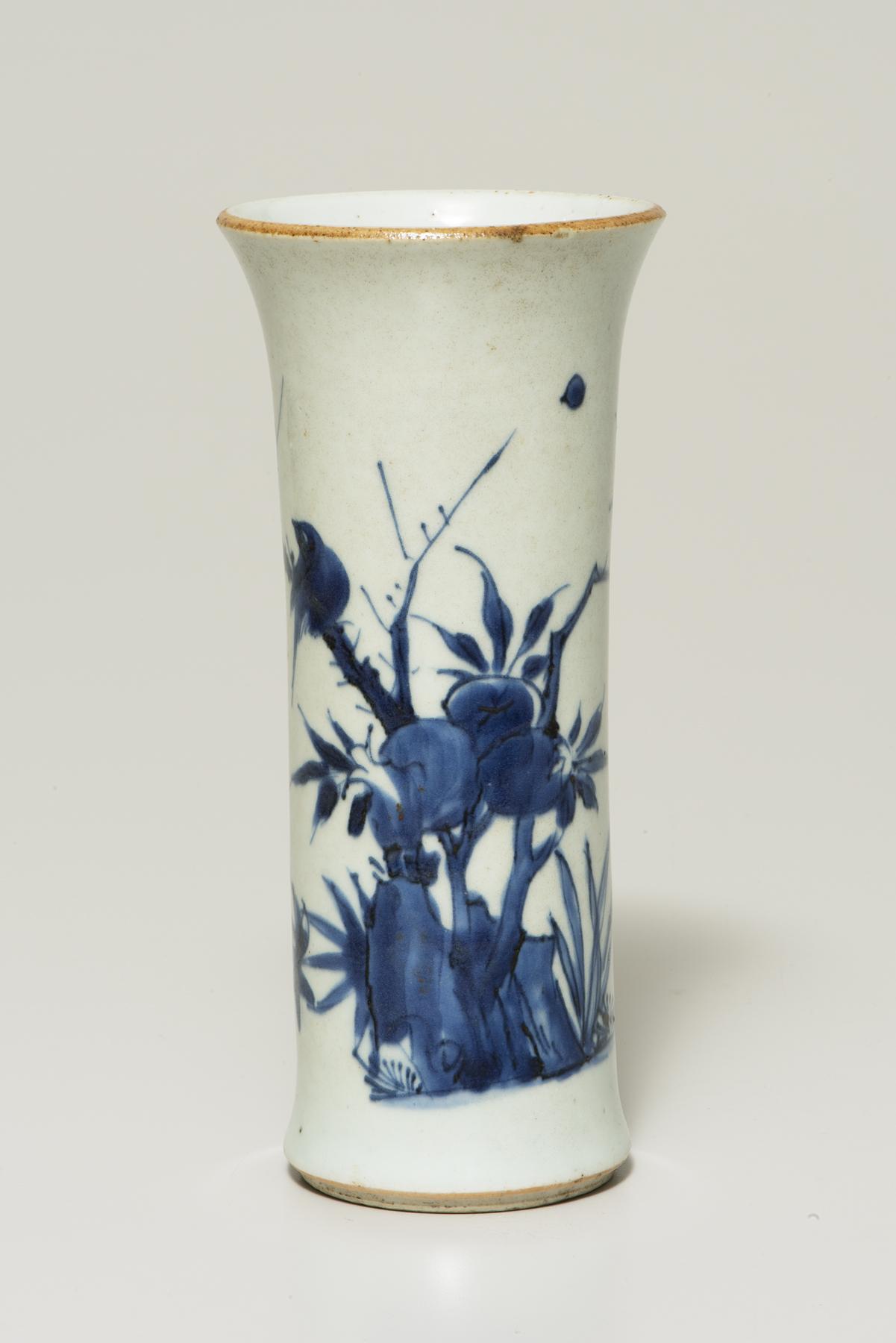 Tall, slender white vase decorated with blue flowers, pomegranates and a tan rim