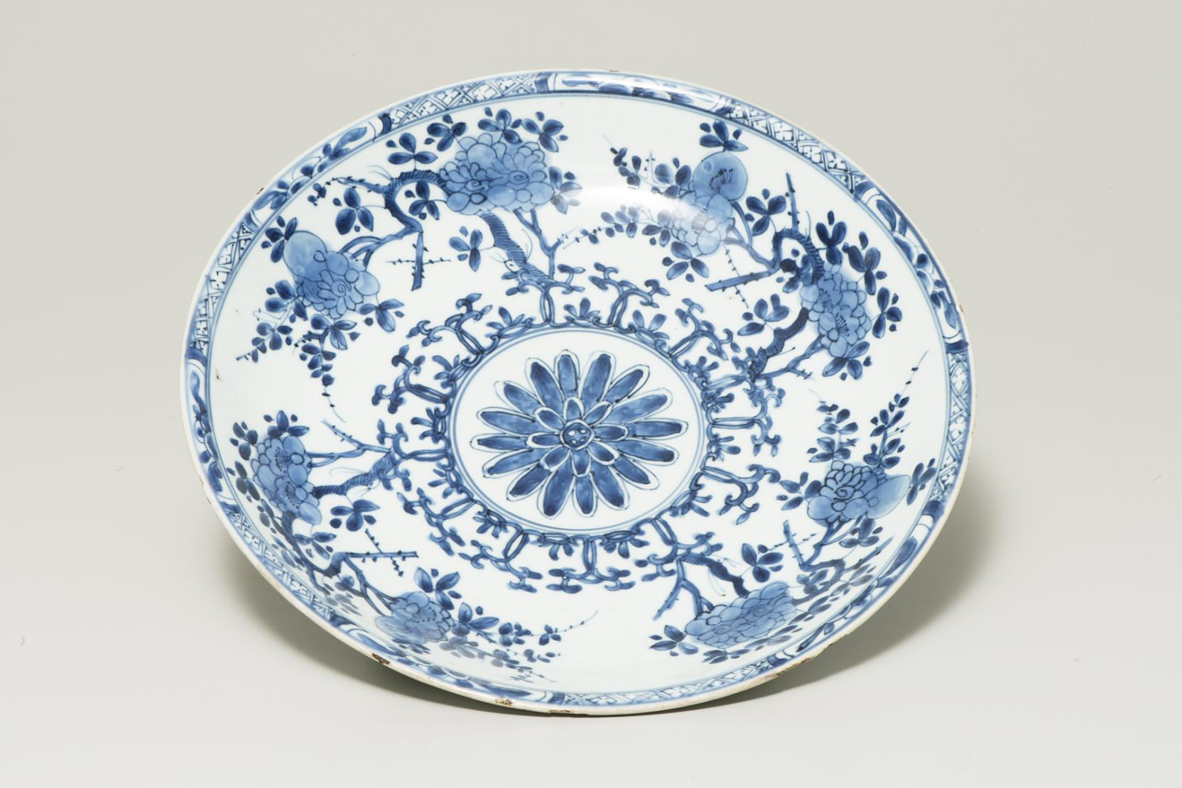 white plate with a blue flower blossom at center bordered by other blue flowers