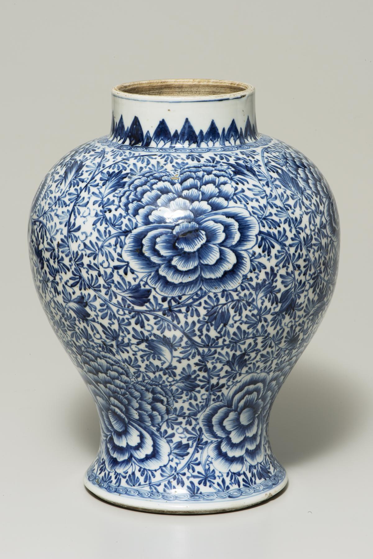 A vase with a wide shoulder over a narrow foot is densely decorated with blue peonies and other flowers