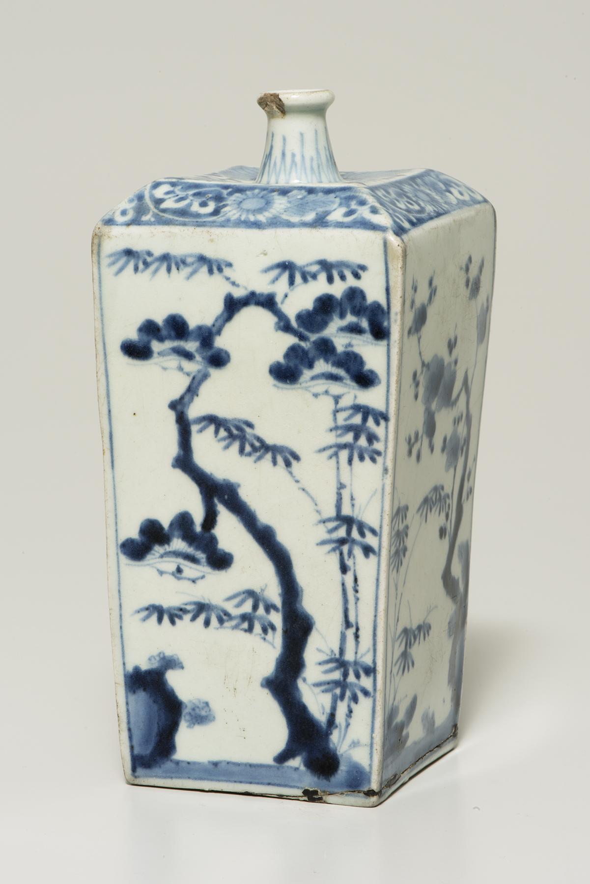 Tall rectangular white bottle decorated with a blue pine tree and bamboo