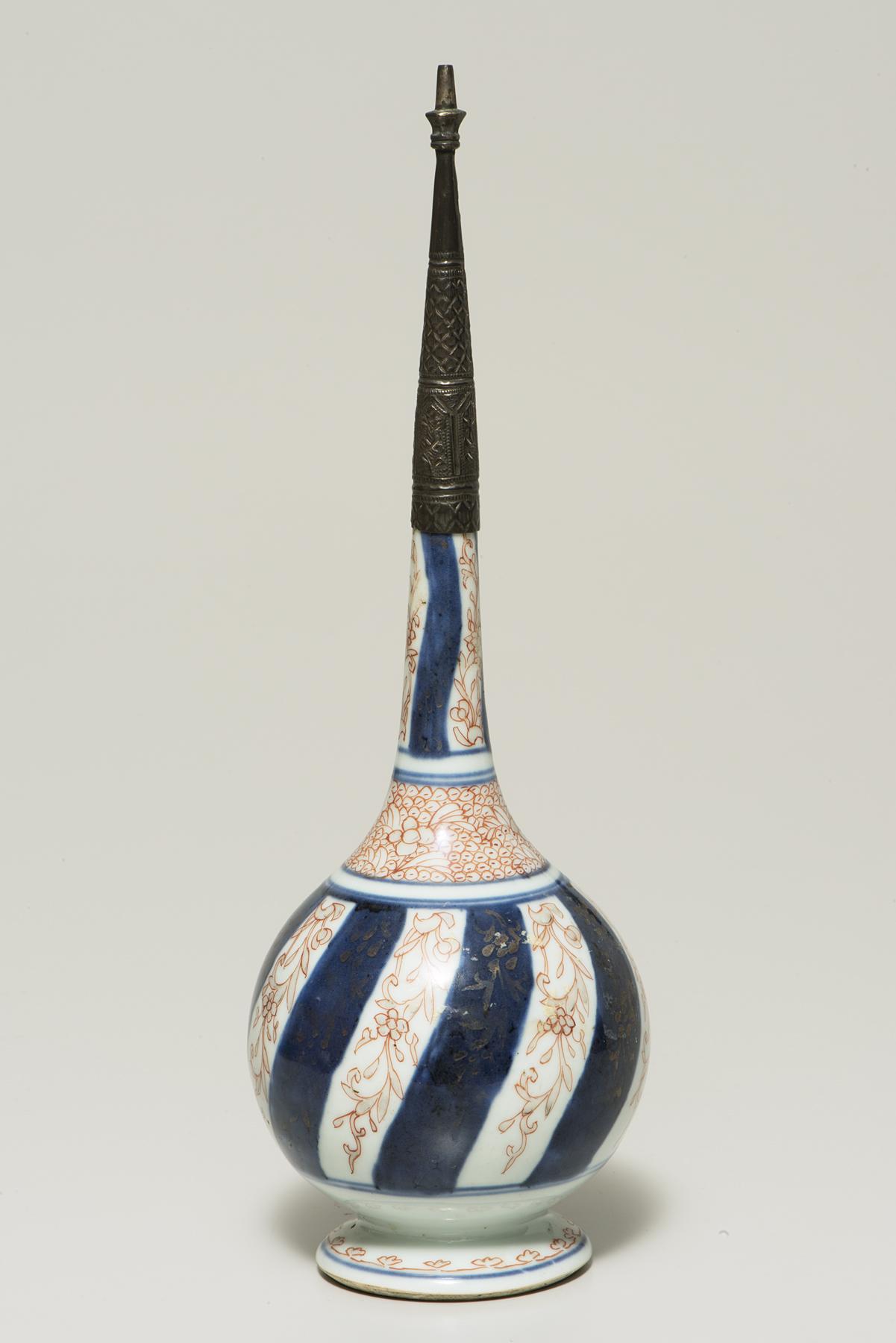 A bulbous bottle decorated with alternating navy stripes and orange flowers has a long neck topped with a long, thin, dark silver cap