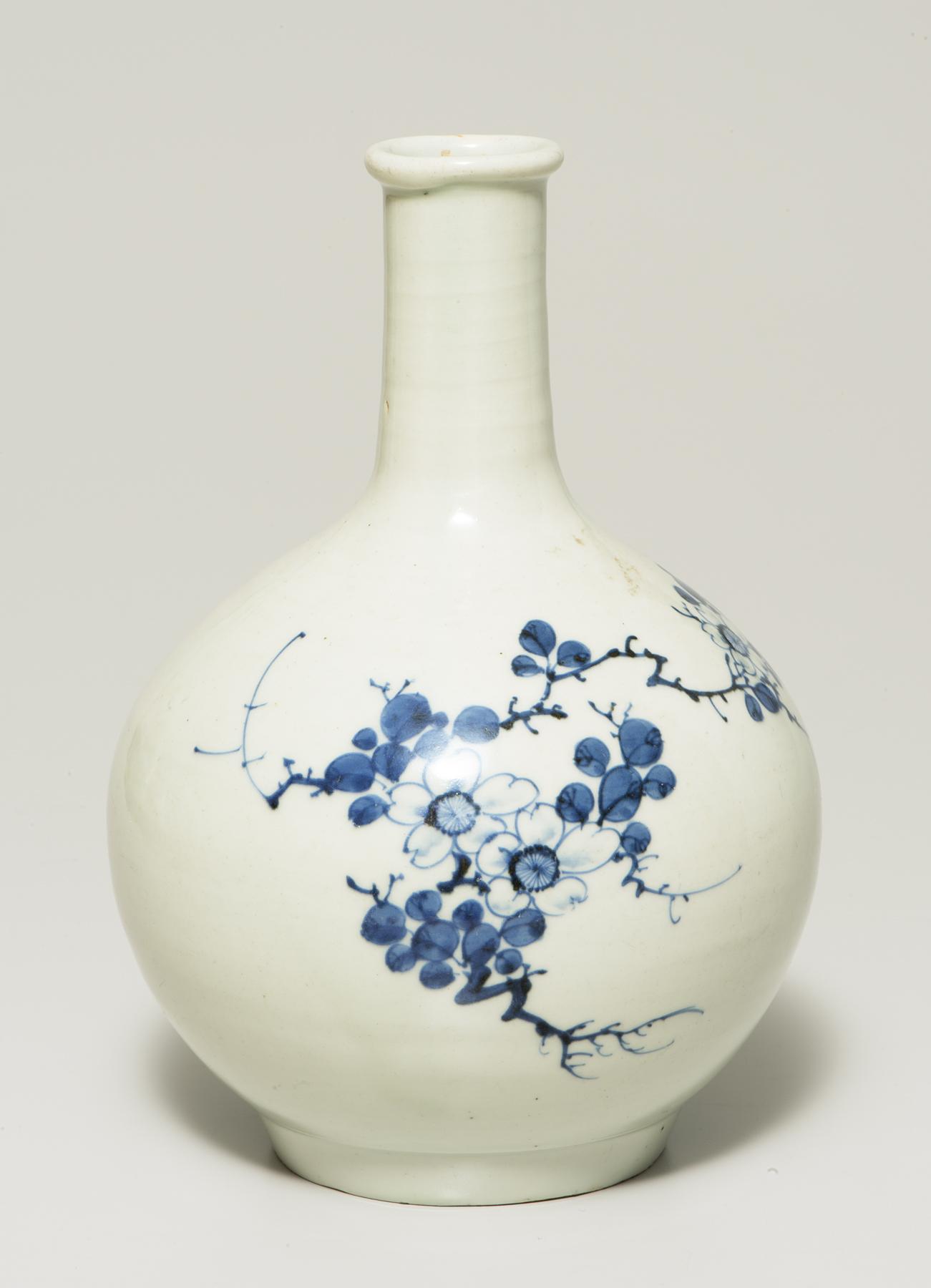 a bulbous white vase with a long, narrow neck is decorated with blue flowering crabapple branches